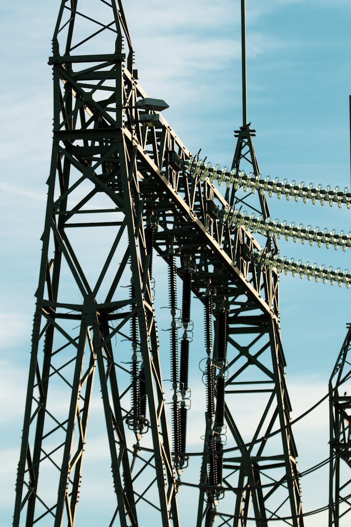 High voltage power transmission towers against a clear blue sky, symbolizing energy and infrastructure.