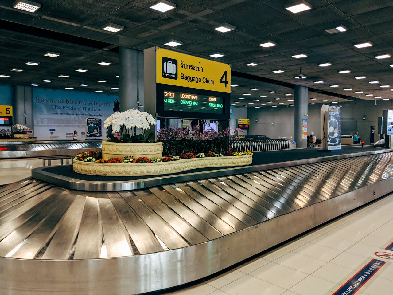 home-hero Modern baggage claim area at Suvarnabhumi Airport in Bangkok with luggage carousel and signage.